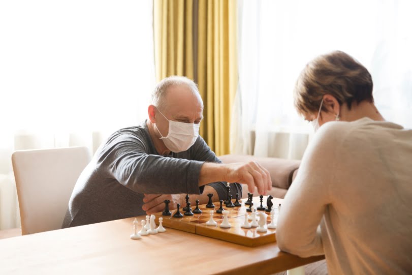 Senior playing checkers with mask (1)